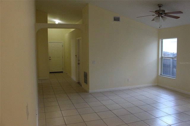 empty room featuring light tile patterned floors, baseboards, visible vents, and a ceiling fan