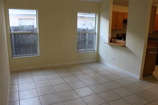 empty room featuring baseboards and light tile patterned flooring