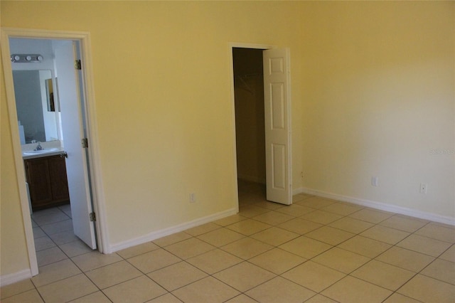 unfurnished room with light tile patterned flooring, a sink, and baseboards