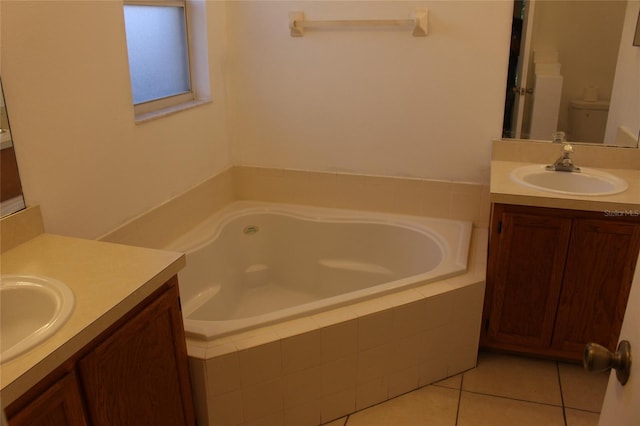 full bath featuring two vanities, a garden tub, a sink, and tile patterned floors