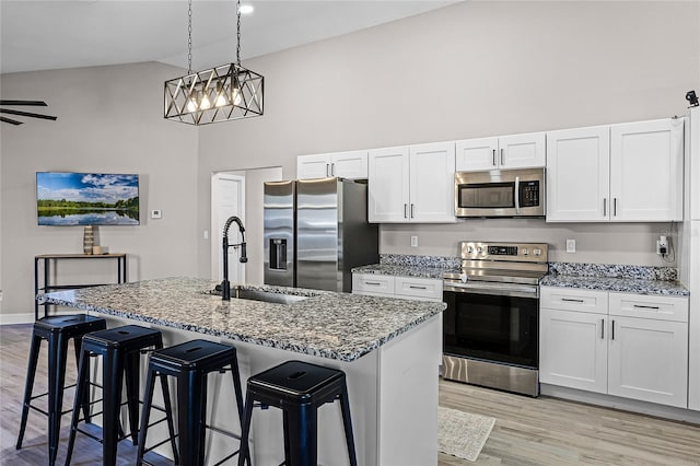 kitchen with high vaulted ceiling, light wood-style flooring, a sink, stainless steel appliances, and dark stone counters