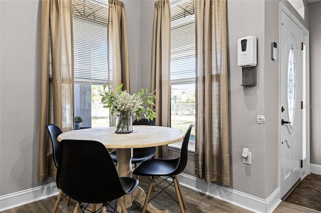 dining area with baseboards, a healthy amount of sunlight, dark wood-style floors, and a textured wall