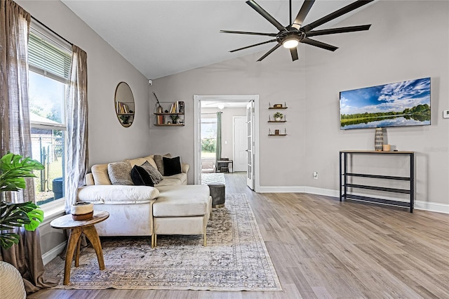 living area with a wealth of natural light, vaulted ceiling, baseboards, and wood finished floors