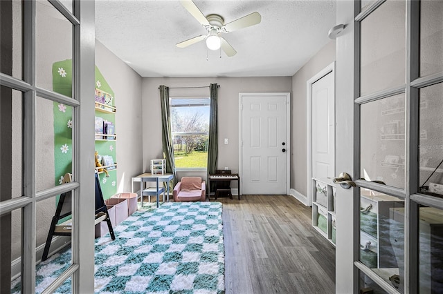 sitting room featuring baseboards, french doors, wood finished floors, a textured ceiling, and a ceiling fan