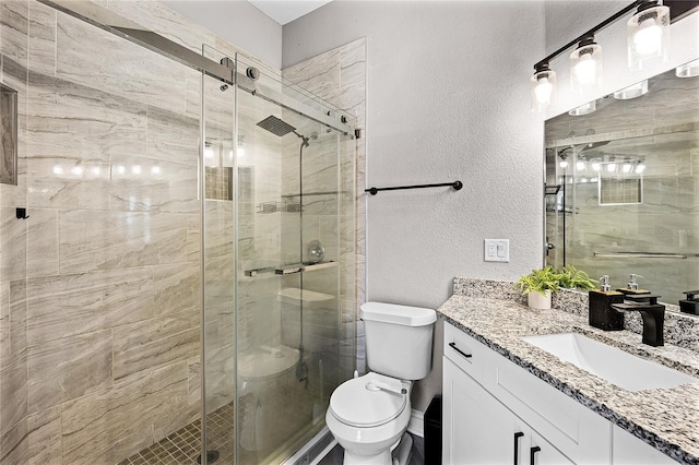 bathroom with a shower stall, toilet, vanity, and a textured wall