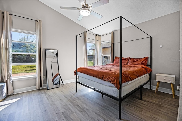 bedroom featuring vaulted ceiling, wood finished floors, baseboards, and ceiling fan