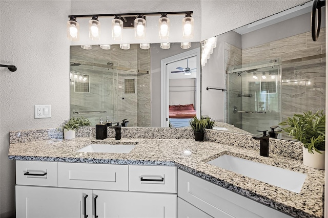 bathroom featuring double vanity, a stall shower, and a sink