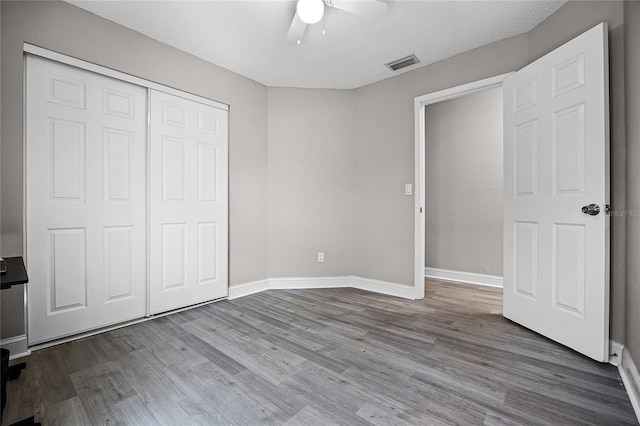 unfurnished bedroom featuring wood finished floors, visible vents, a closet, and baseboards