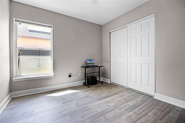 unfurnished bedroom with wood finished floors, a closet, and baseboards