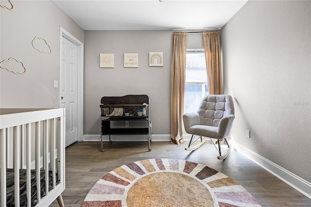 bedroom with baseboards, wood finished floors, and a textured wall