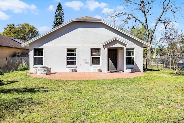 back of house featuring a lawn, fence, and stucco siding