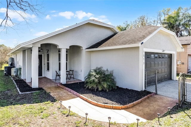 ranch-style home with roof with shingles, a porch, central AC, stucco siding, and a garage