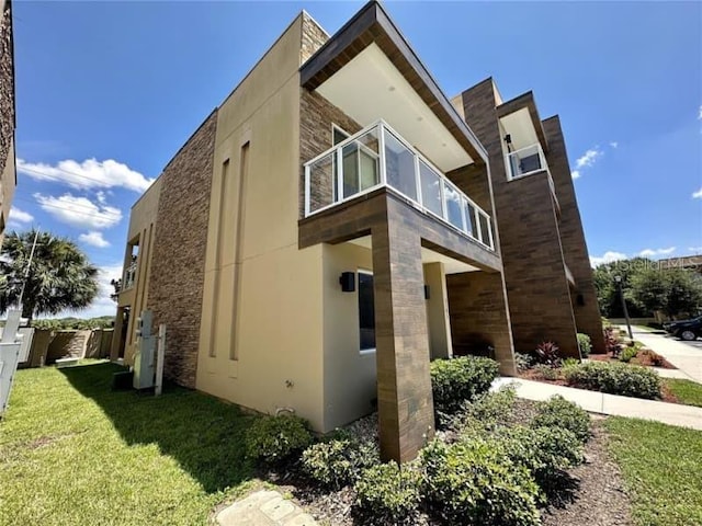 view of home's exterior featuring a lawn, a balcony, and stucco siding