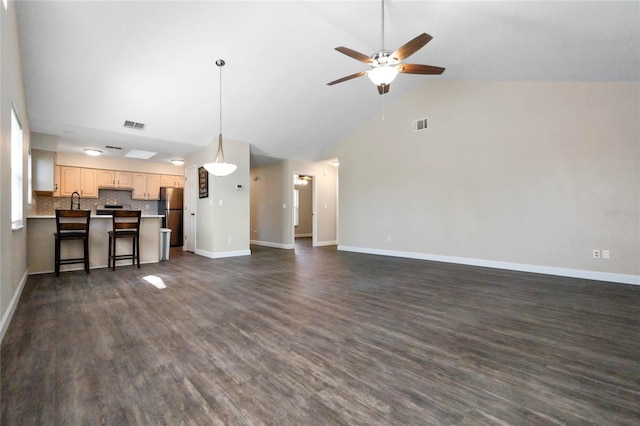 unfurnished living room with dark wood-style floors, a ceiling fan, and baseboards