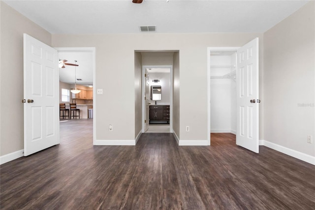 unfurnished bedroom with dark wood-style flooring, visible vents, baseboards, and ensuite bathroom