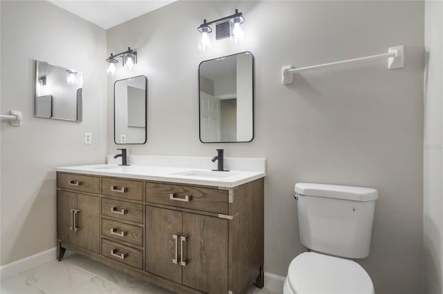 bathroom with toilet, marble finish floor, baseboards, and a sink