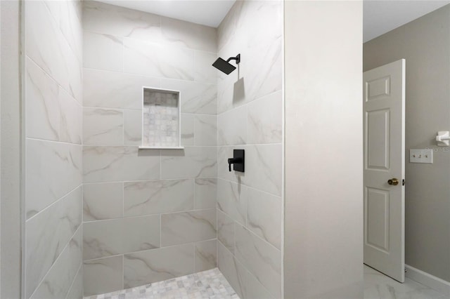 full bathroom featuring marble finish floor and a tile shower