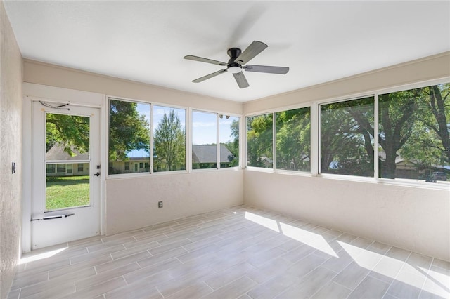 unfurnished sunroom featuring a healthy amount of sunlight and ceiling fan