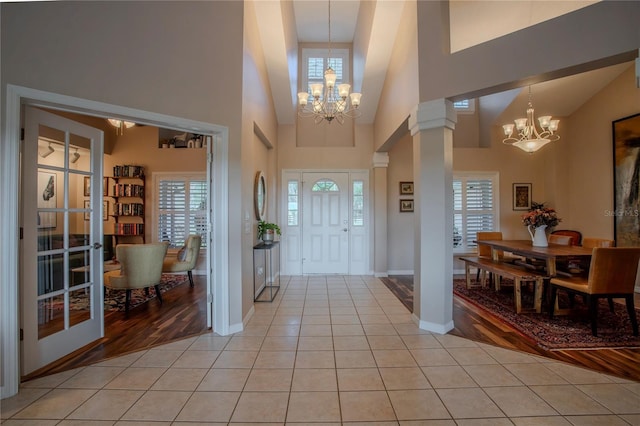 entryway with light tile patterned floors, decorative columns, and a notable chandelier