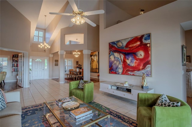 tiled living room featuring decorative columns, a high ceiling, and ceiling fan with notable chandelier