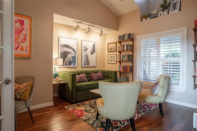 living area featuring dark wood finished floors, track lighting, baseboards, and vaulted ceiling