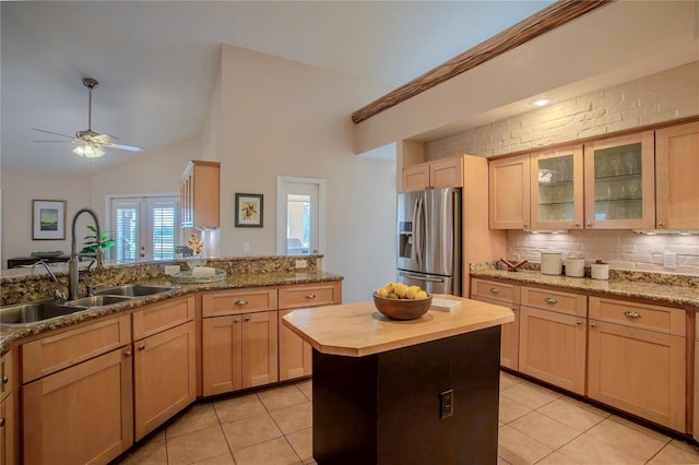 kitchen with stainless steel fridge with ice dispenser, light brown cabinetry, butcher block counters, light tile patterned floors, and a sink