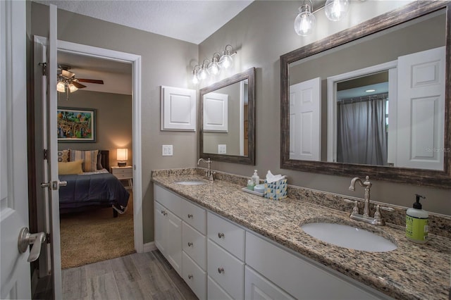 ensuite bathroom with connected bathroom, wood finished floors, a ceiling fan, and a sink