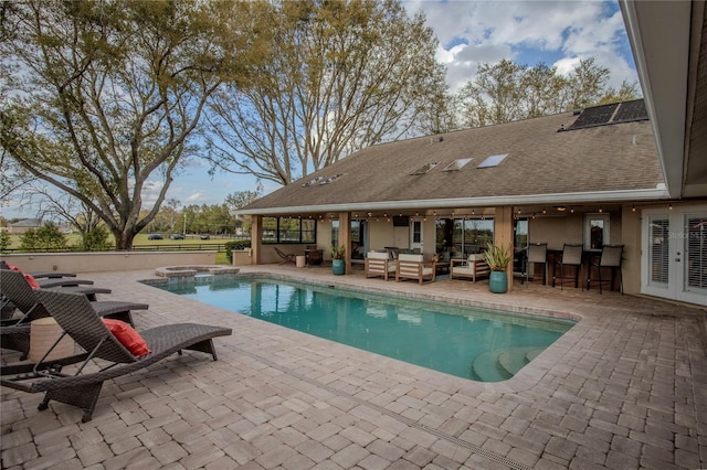 outdoor pool featuring an in ground hot tub, french doors, a patio area, outdoor dry bar, and an outdoor hangout area