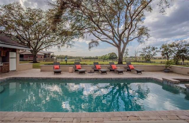 outdoor pool with a patio and fence