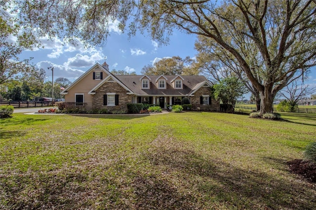 view of front facade featuring a front lawn, fence, and stone siding