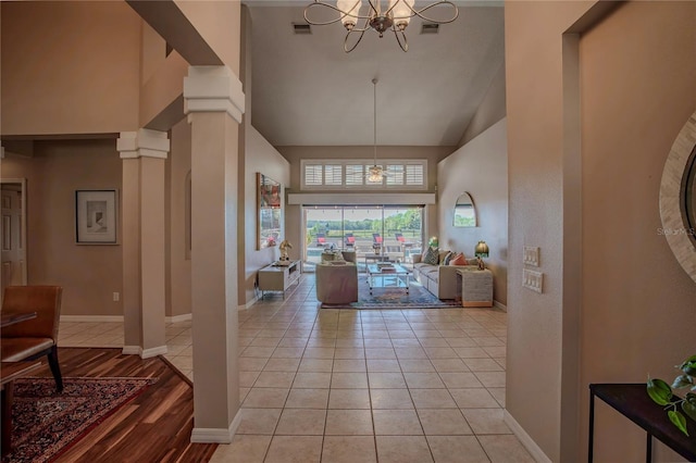 living area with an inviting chandelier, light tile patterned flooring, visible vents, and high vaulted ceiling