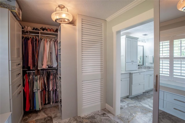 bathroom featuring vanity, ornamental molding, a textured ceiling, a walk in closet, and marble finish floor