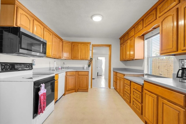 kitchen with light countertops, white appliances, a sink, and brown cabinets