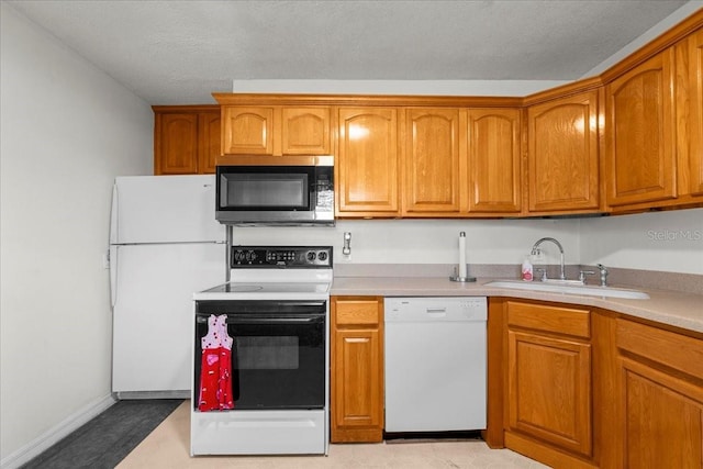 kitchen with brown cabinetry, white appliances, light countertops, and a sink