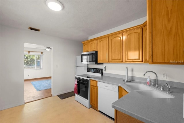 kitchen with range with electric stovetop, a sink, visible vents, baseboards, and dishwasher