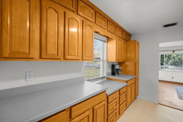 kitchen with brown cabinets, baseboards, visible vents, and light countertops