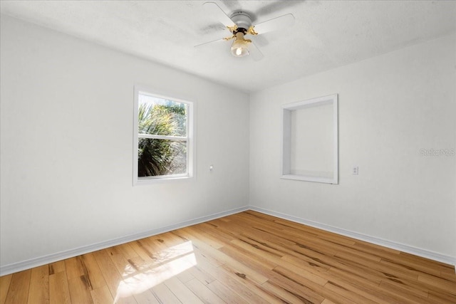 spare room featuring a ceiling fan, baseboards, and hardwood / wood-style floors