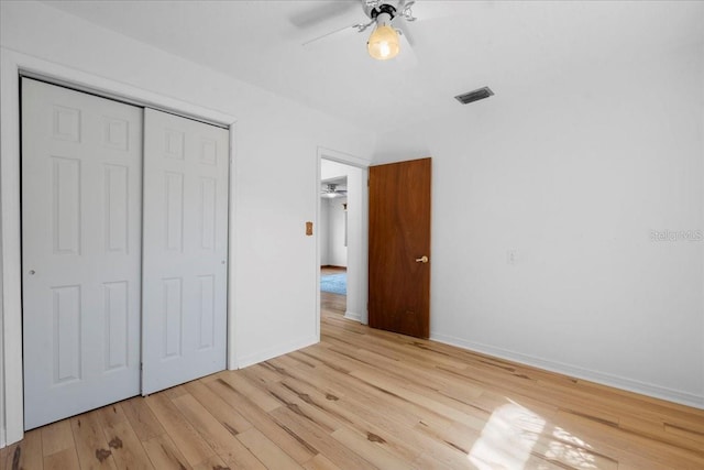 unfurnished bedroom with a closet, visible vents, light wood-style flooring, ceiling fan, and baseboards