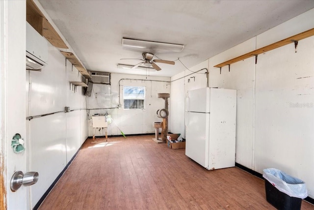 below grade area featuring light wood finished floors, a sink, freestanding refrigerator, and a ceiling fan