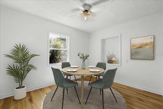 dining area featuring ceiling fan, a textured ceiling, wood finished floors, and baseboards