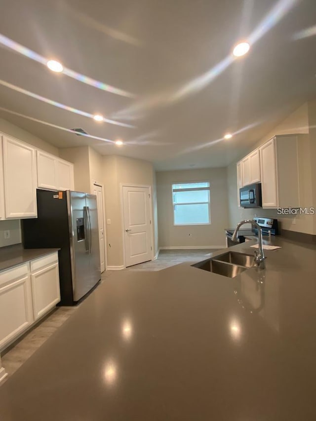 kitchen with stainless steel appliances, a sink, visible vents, and white cabinetry