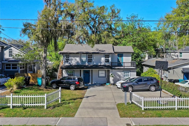 traditional home with a fenced front yard, driveway, and stucco siding