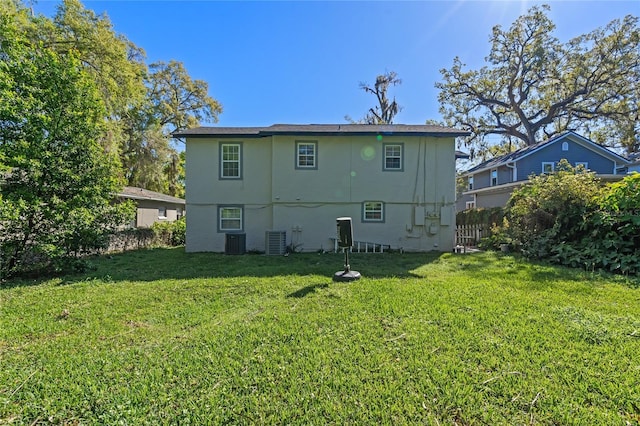 rear view of house featuring a lawn, central AC unit, and stucco siding