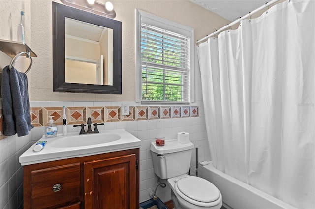 bathroom with a textured wall, toilet, vanity, tile walls, and shower / bath combo