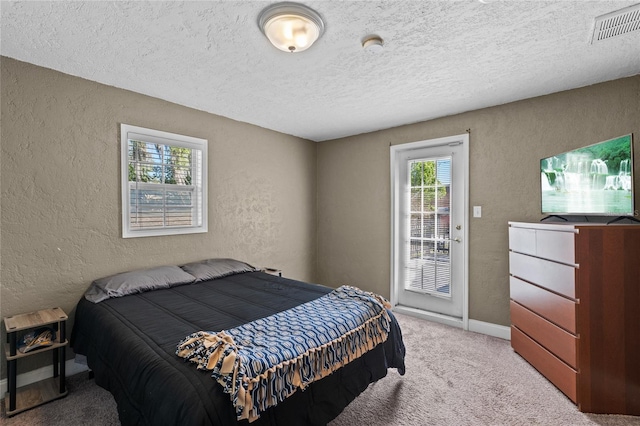 bedroom with carpet floors, visible vents, a textured ceiling, and a textured wall