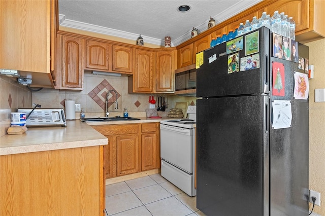 kitchen with white range with electric stovetop, stainless steel microwave, freestanding refrigerator, light countertops, and a sink