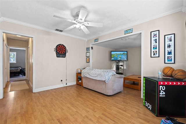 living area featuring light wood-type flooring, ceiling fan, visible vents, and ornamental molding