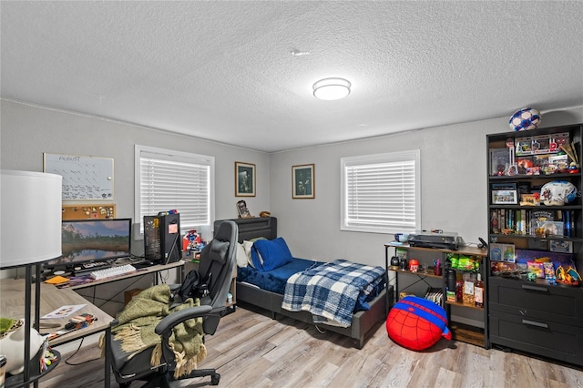 bedroom with a textured ceiling and wood finished floors