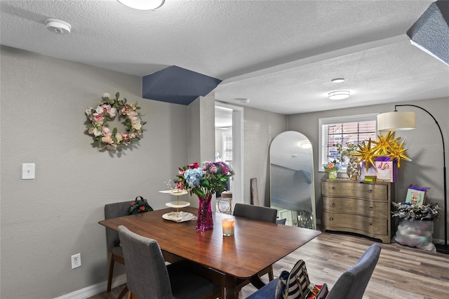 dining area with a textured ceiling, wood finished floors, and baseboards