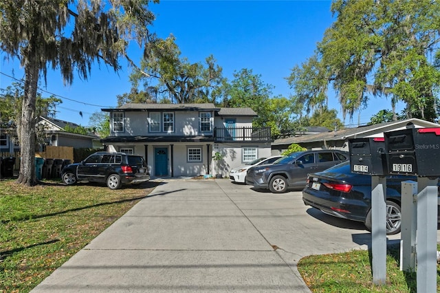 traditional-style home with uncovered parking, a front lawn, and stucco siding